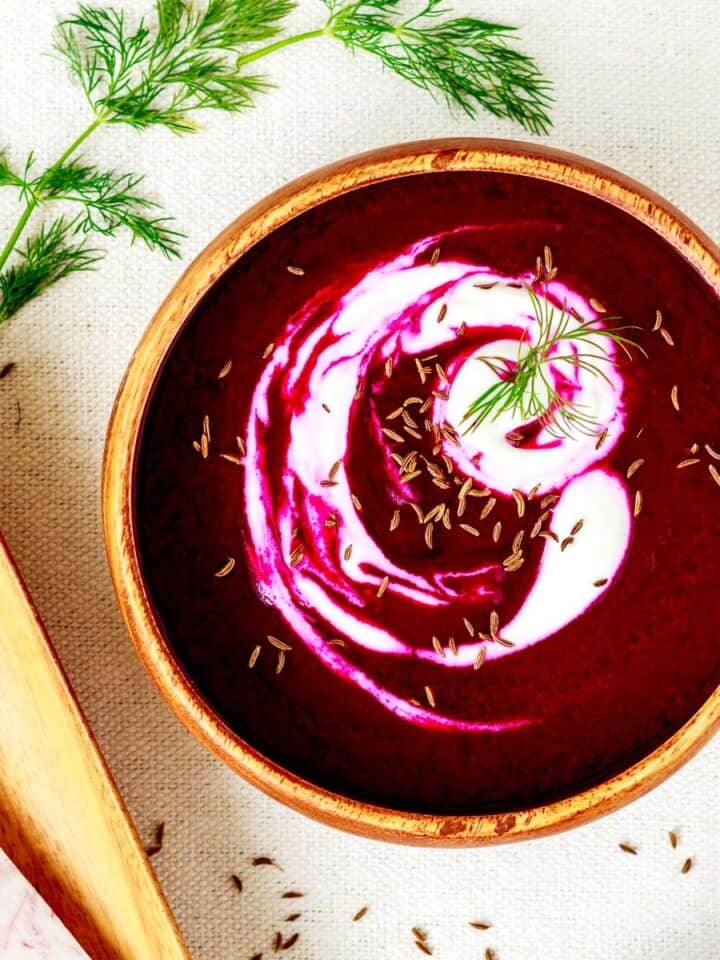 Bowl of beet and taro soup with vegan sour cream swirl.