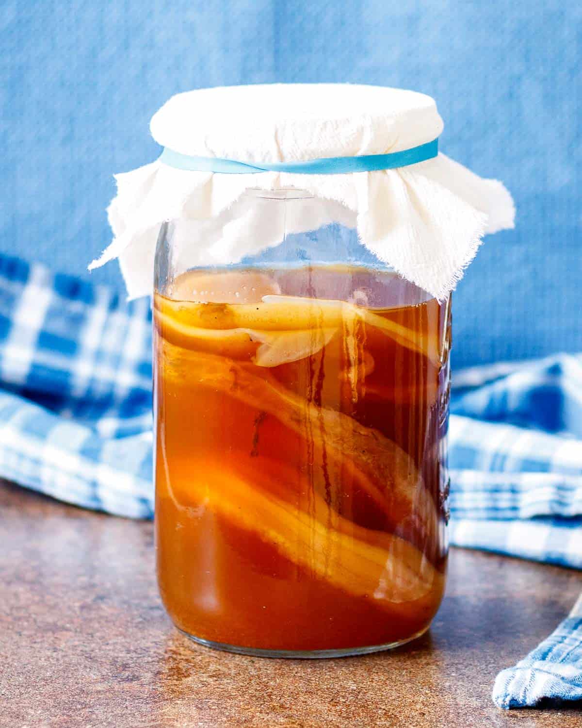 Jar of sweet tea with several SCOBY's submerged in it.