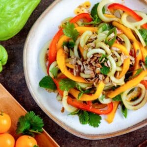 Spiraled raw vegetable and papaya salad on a plate.