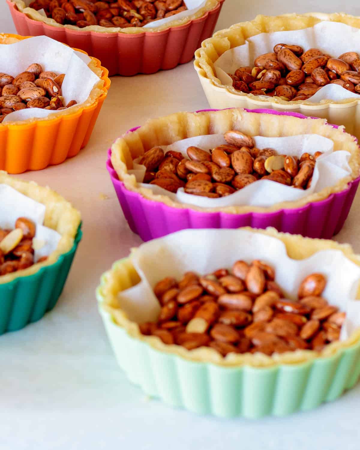 Tart shells shaped with parchment paper and beans.