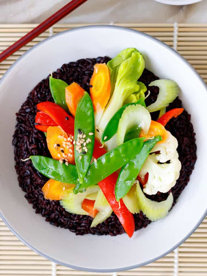 Colorful steamed vegetables with black rice and creamy sesame sauce.