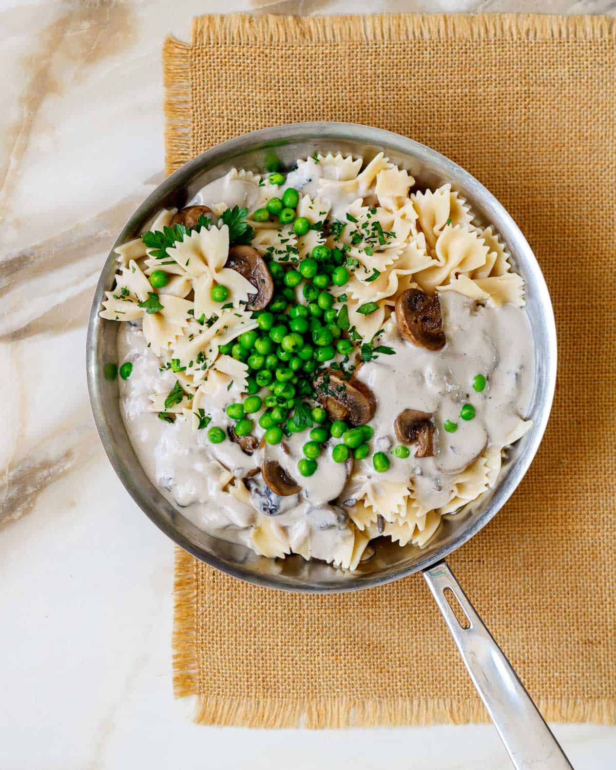 Pan of farfalle pasta with peas in a creamy mushroom sauce.