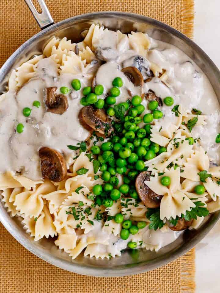 Pan of farfalle pasta with peas in a creamy mushroom sauce.