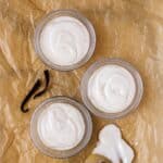 Three bowls of smooth vanilla pudding on crumpled parchment.