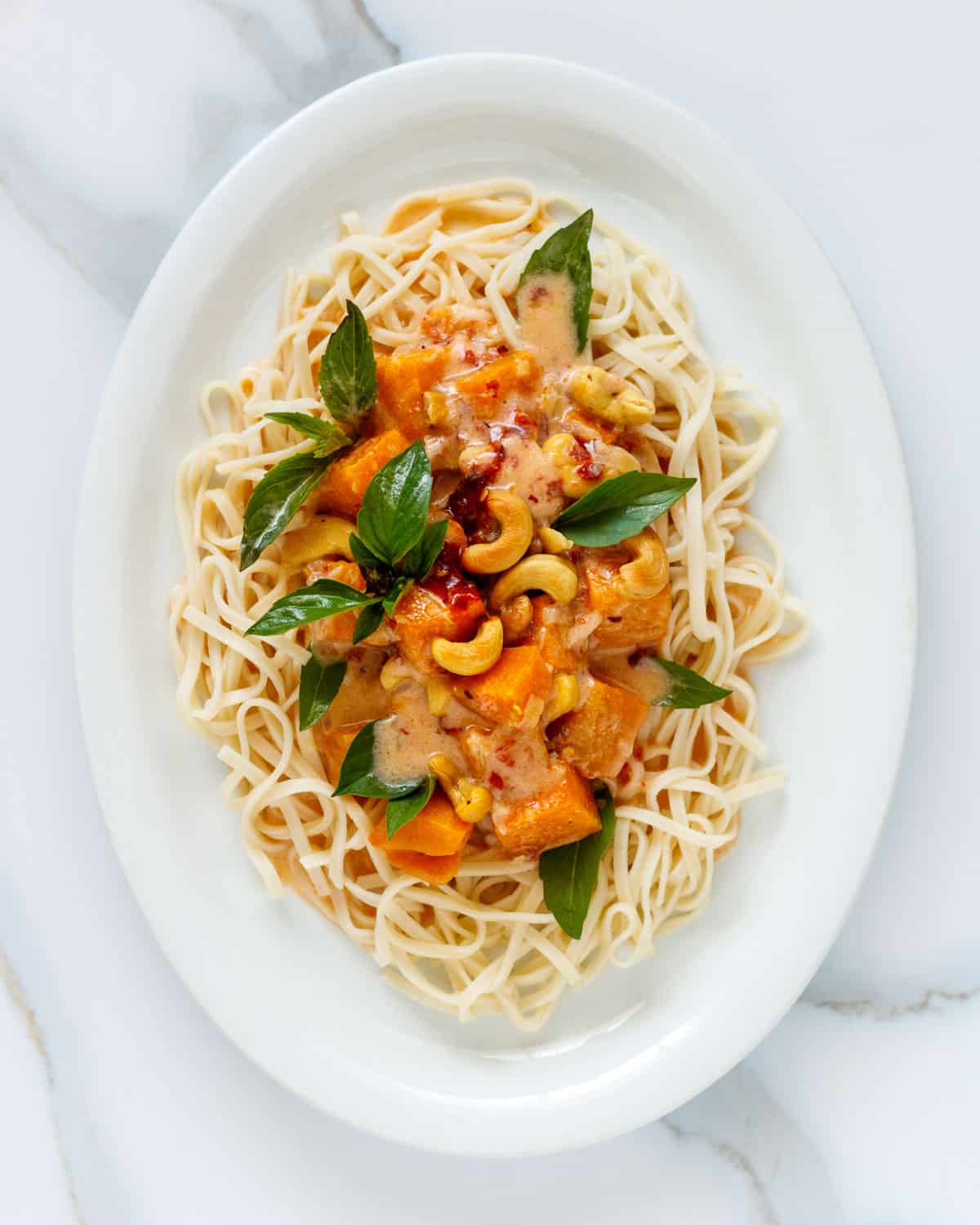 Thin noodles topped with colorful pumpkin red curry.