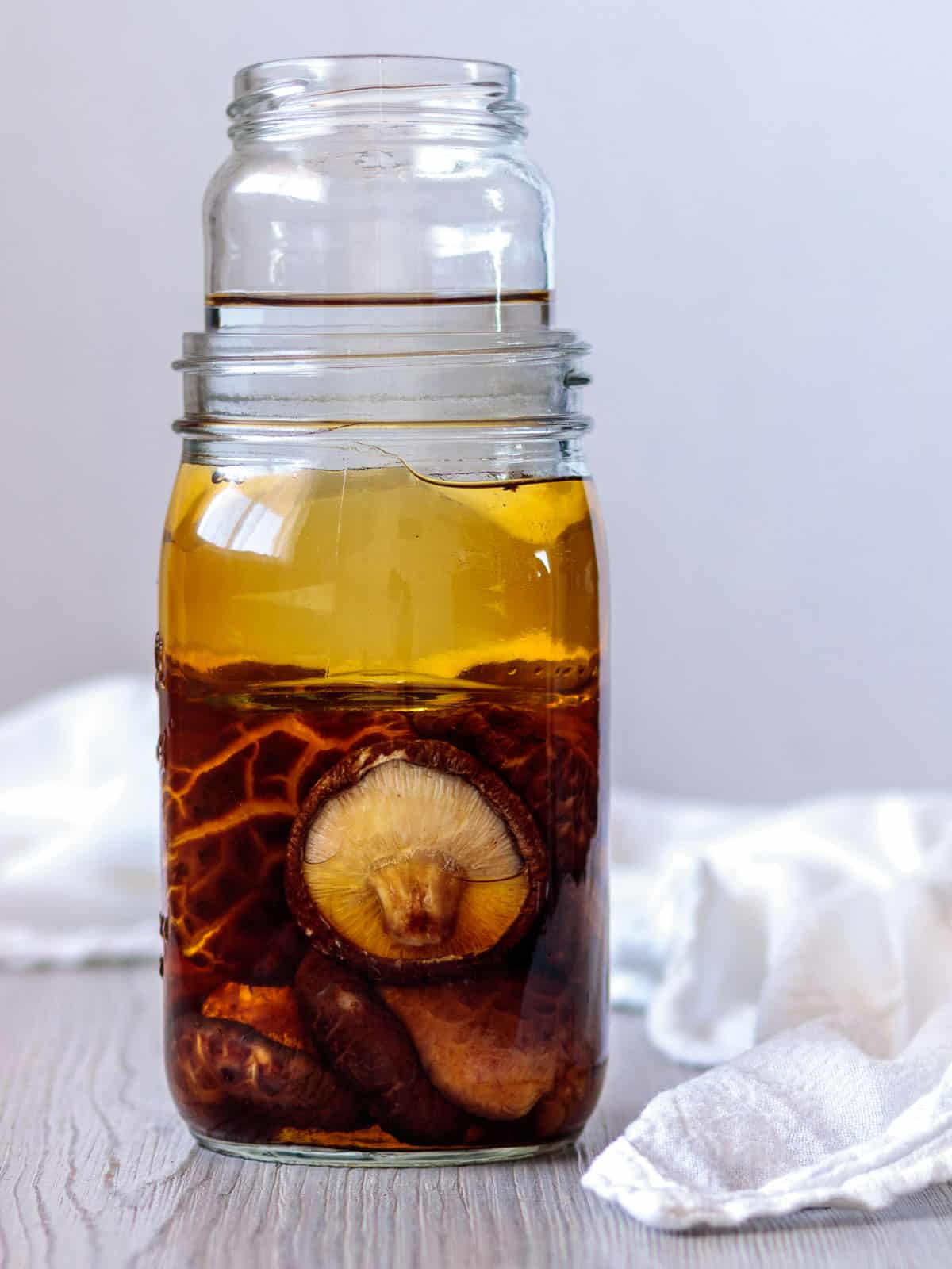 Jar filled with water and submerged dry shiitake that has soaked.