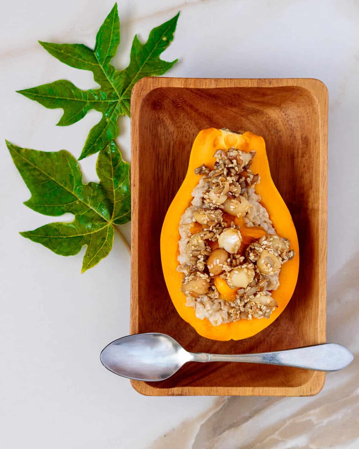 Half a papaya filled with oatmeal and topped with candied nuts.