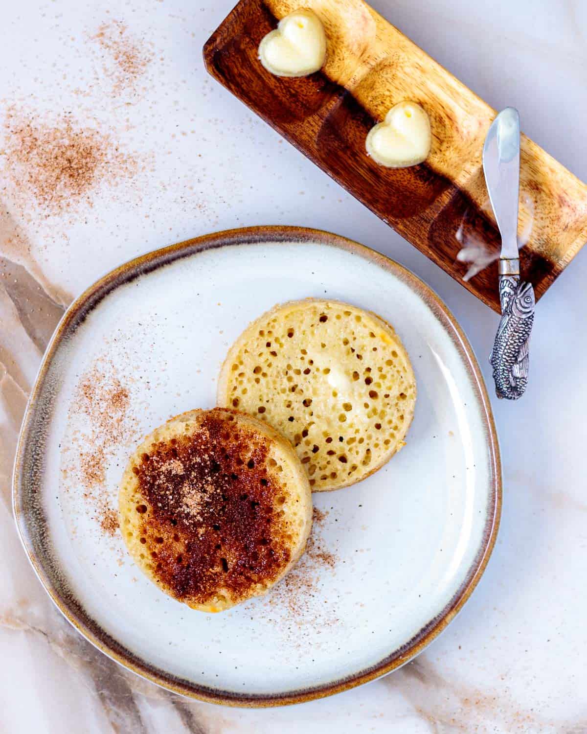 Two buttered crumpets with cinnamon sugar on half.