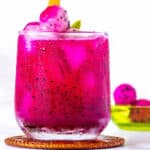 Glass of pink pitaya juice poured over ice.