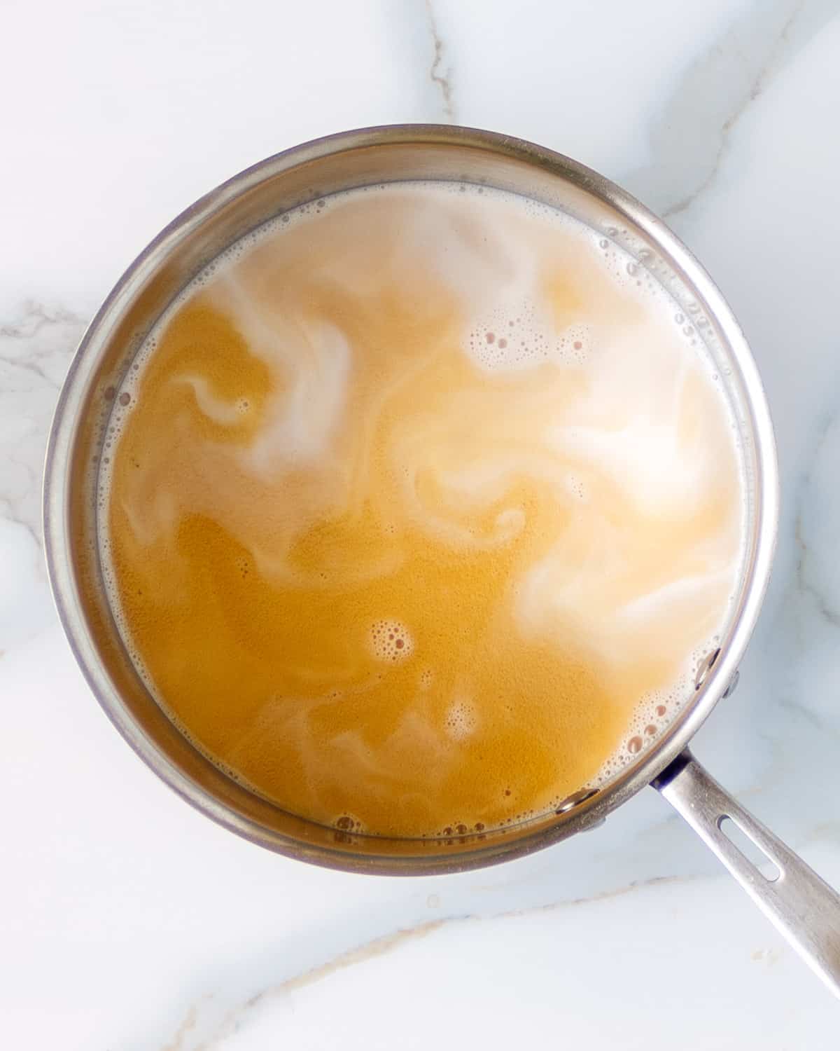 Pan of spiced tea swirled with macadamia nut milk.