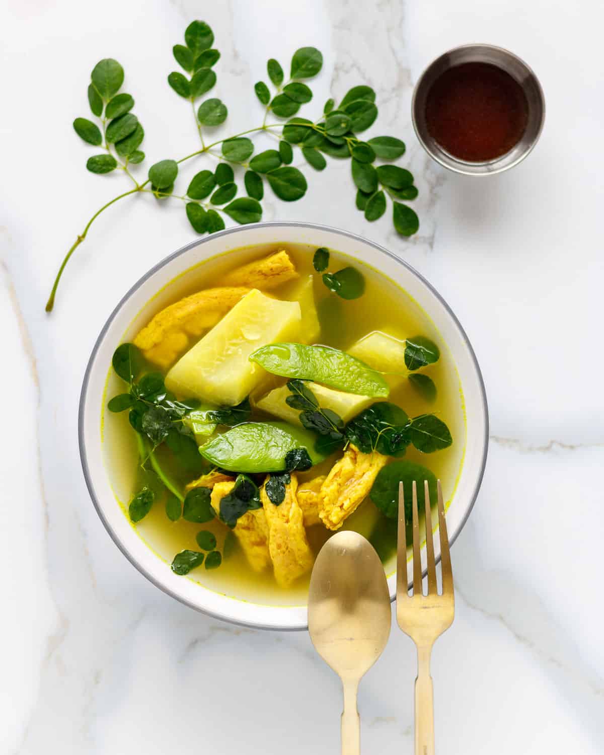 Bowl of vegan tinola with moringa leaves, soy curls and green papaya.