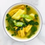 Bowl of vegan tinola with moringa leaves, soy curls and green papaya.