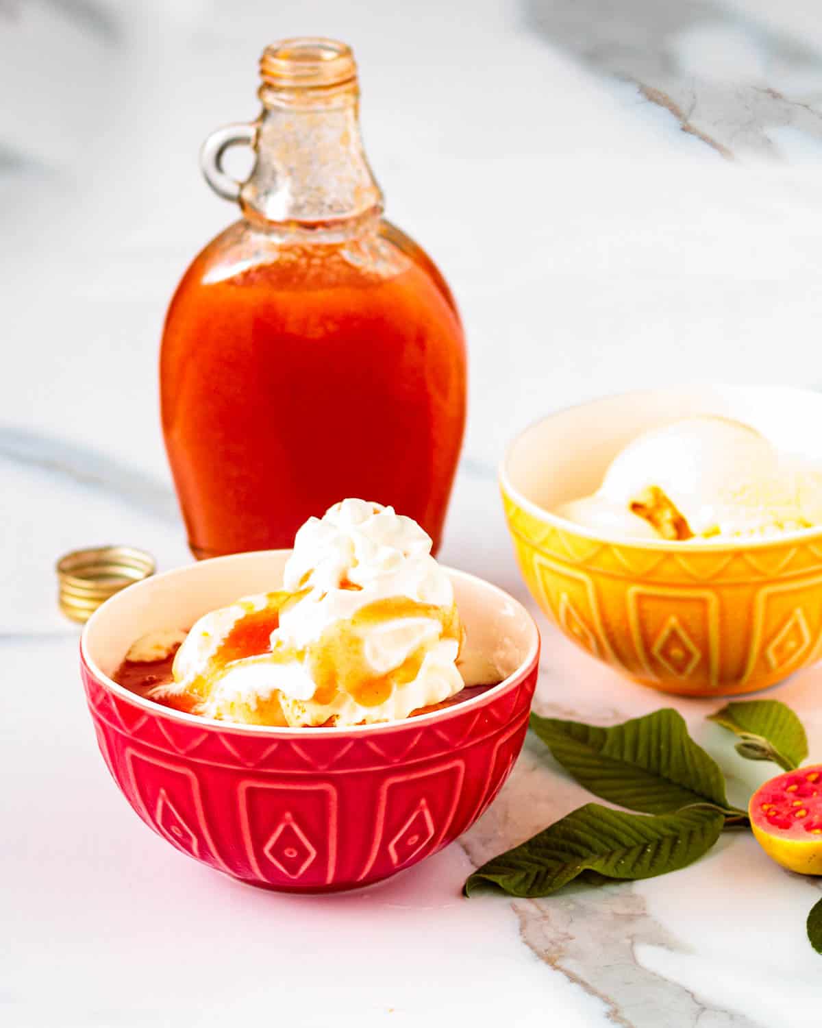 Bowl of vanilla ice cream with guava syrup on top.