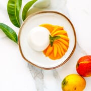 Soft coconut panna cotta with mango slices and sauce.